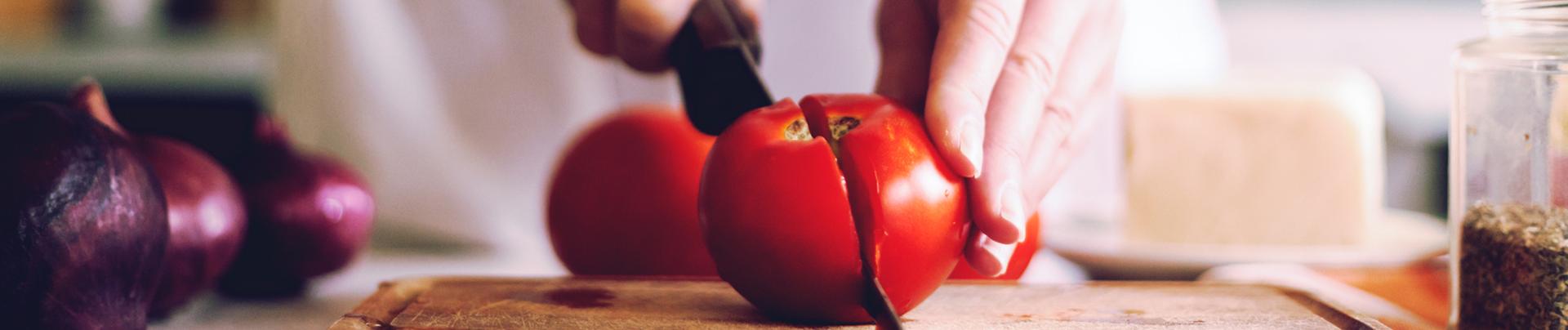 Mains de femme coupant une tomate
